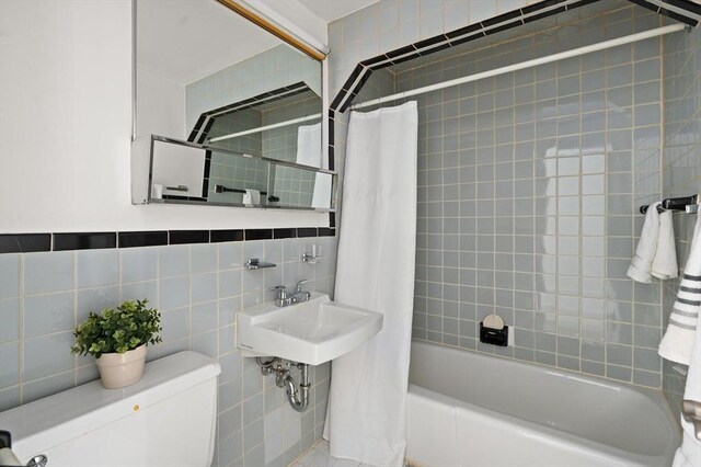 bathroom with a sink, tile walls, shower / bath combo, and toilet