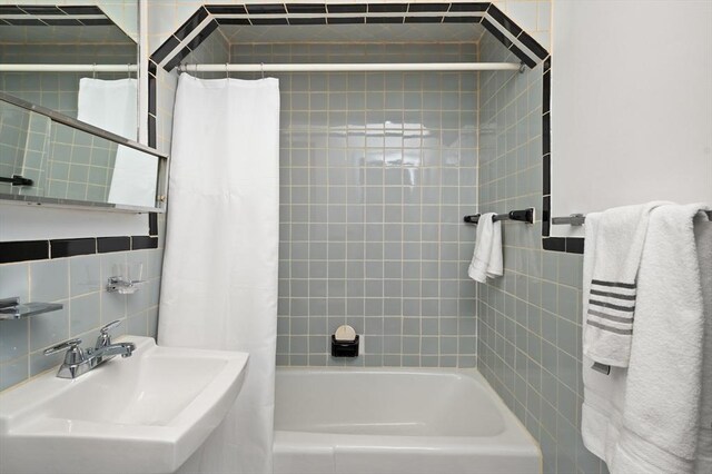full bathroom with tile walls, a sink, and shower / tub combo