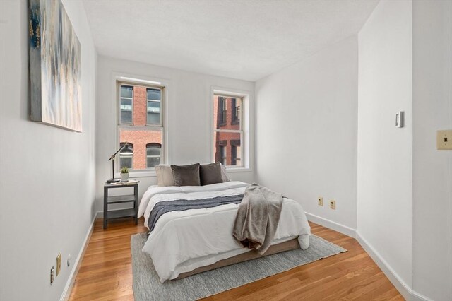 bedroom featuring baseboards, multiple windows, and light wood-type flooring