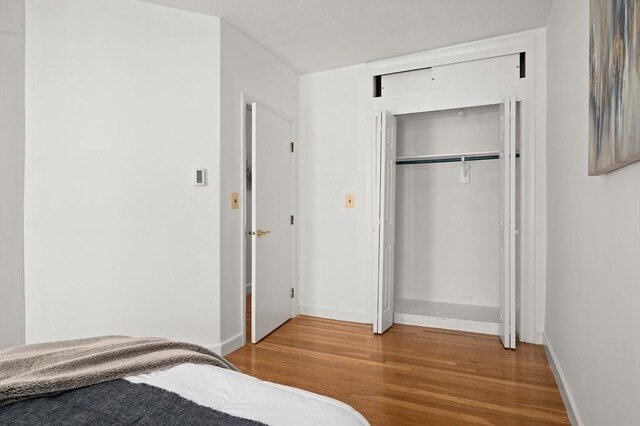 bedroom featuring baseboards, a closet, and wood finished floors