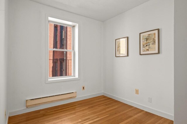 unfurnished room featuring light wood-type flooring, baseboards, and baseboard heating
