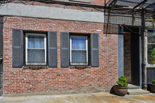 view of side of property featuring a pergola and brick siding