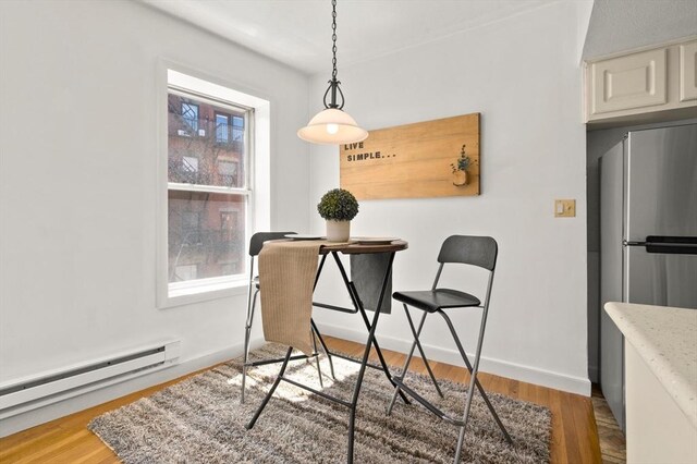 dining room with light wood-style floors, baseboards, and a baseboard radiator