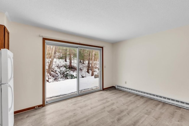 spare room with a baseboard heating unit, light hardwood / wood-style flooring, and a textured ceiling