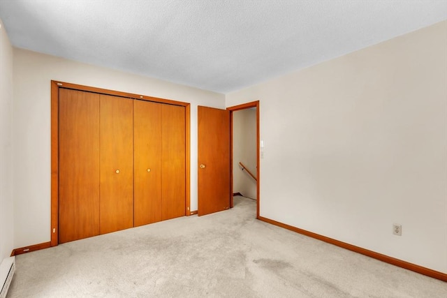 unfurnished bedroom featuring a baseboard radiator, light colored carpet, a closet, and a textured ceiling