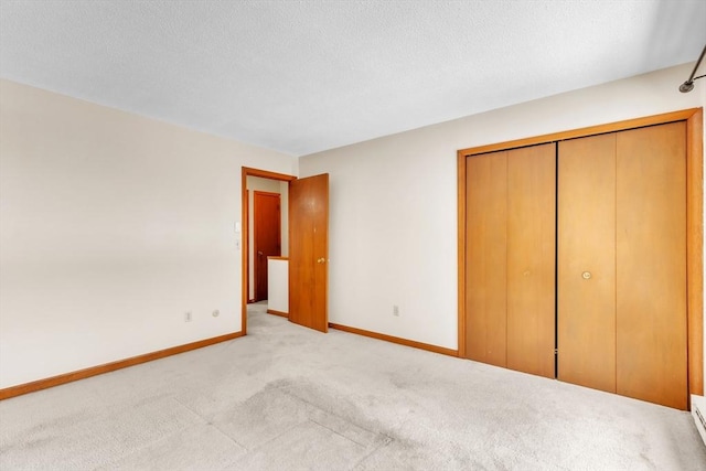 unfurnished bedroom featuring a baseboard radiator, light carpet, a textured ceiling, and a closet