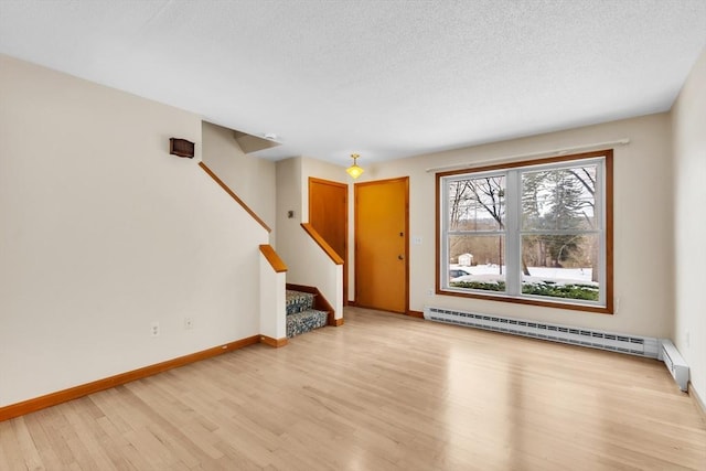 unfurnished living room with a baseboard radiator, light hardwood / wood-style floors, and a textured ceiling