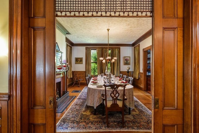 dining space featuring ornamental molding, a chandelier, wood-type flooring, and a textured ceiling