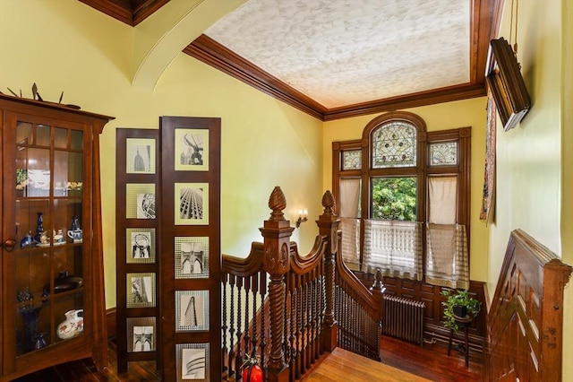 entrance foyer with crown molding, wood-type flooring, radiator heating unit, and a textured ceiling