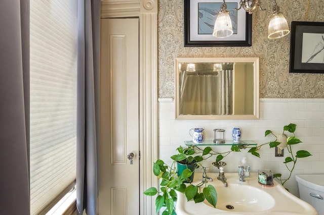 bathroom with sink, tile walls, and toilet