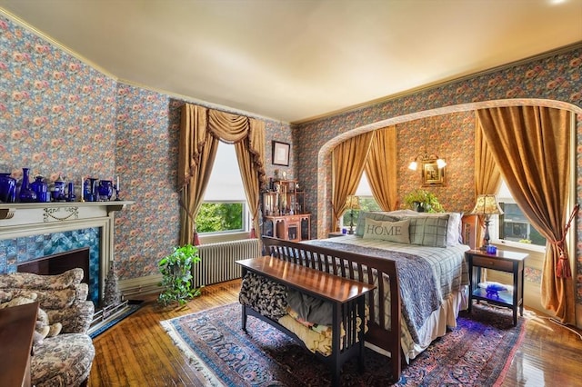 bedroom with a fireplace, hardwood / wood-style flooring, radiator heating unit, and ornamental molding