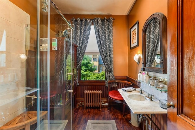 bathroom with radiator, sink, hardwood / wood-style flooring, an enclosed shower, and toilet