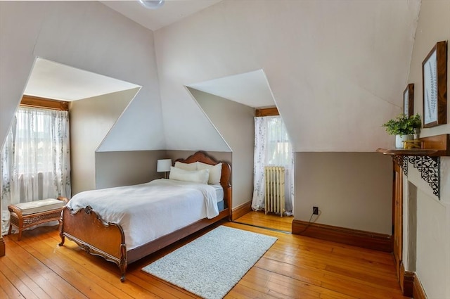 bedroom with lofted ceiling, radiator, and light hardwood / wood-style floors