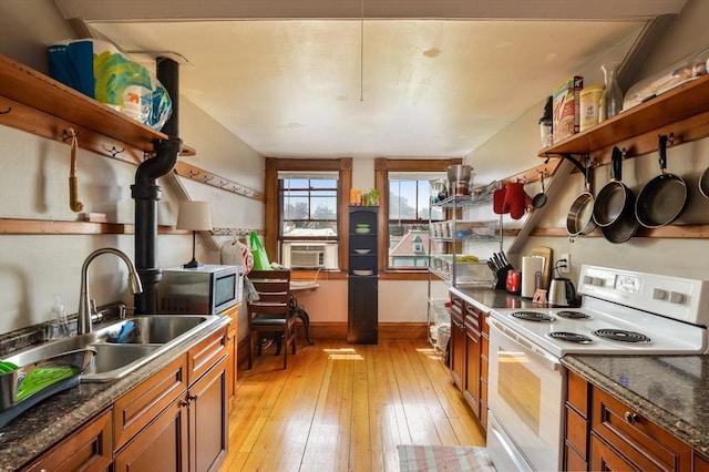 kitchen with white electric stove, sink, dark stone counters, and light hardwood / wood-style flooring