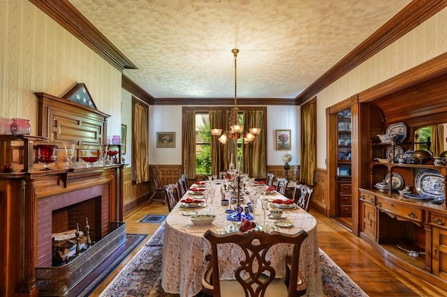 dining area with an inviting chandelier, ornamental molding, a fireplace, and wood-type flooring