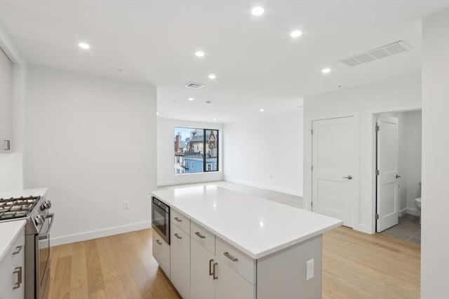 256 Dorchester St Unit 408, Boston, MA 02127 - kitchen featuring stainless steel gas stove, black microwave, a center island, light wood-type flooring, and recessed lighting