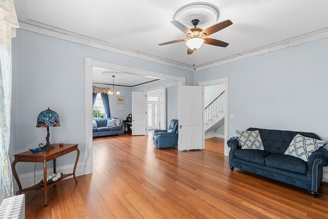 41 Edwards St, Southbridge, MA 01550 - living room featuring stairway, radiator, light wood-style flooring, a ceiling fan, and crown molding