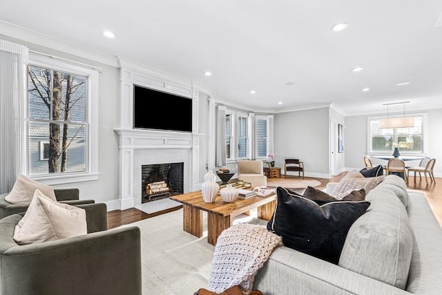 living room with a healthy amount of sunlight, light hardwood / wood-style floors, and crown molding