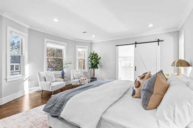 bedroom featuring ornamental molding, hardwood / wood-style floors, and a barn door