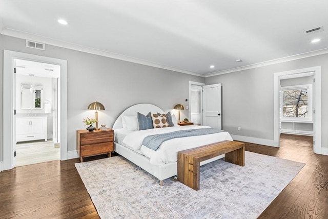 bedroom with a walk in closet, connected bathroom, ornamental molding, and dark wood-type flooring