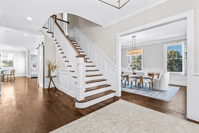 staircase with ornamental molding and hardwood / wood-style floors