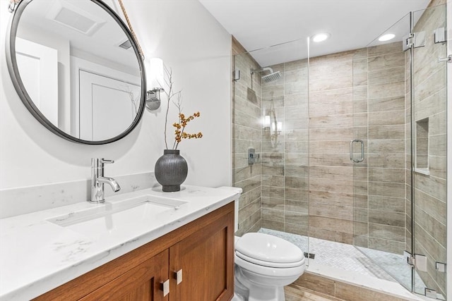 bathroom with toilet, a shower with door, and vanity