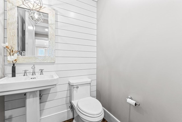 bathroom with wood walls and toilet