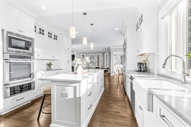 kitchen with stainless steel appliances, white cabinets, backsplash, hanging light fixtures, and a kitchen island