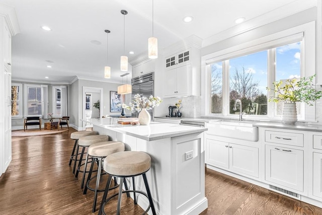 kitchen with stainless steel built in fridge, pendant lighting, a center island, white cabinetry, and sink