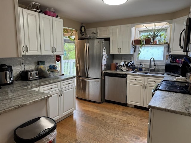 kitchen featuring appliances with stainless steel finishes, a sink, white cabinets, and backsplash