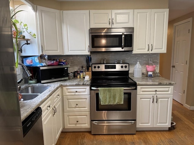 kitchen featuring appliances with stainless steel finishes, white cabinets, tasteful backsplash, and light wood-type flooring