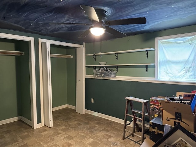 bedroom featuring multiple closets, baseboards, and stone finish floors