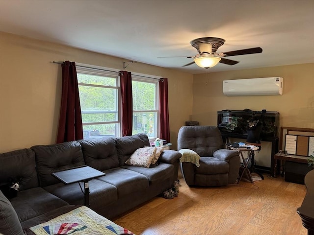 living room featuring a wall unit AC, light wood-style flooring, and a ceiling fan