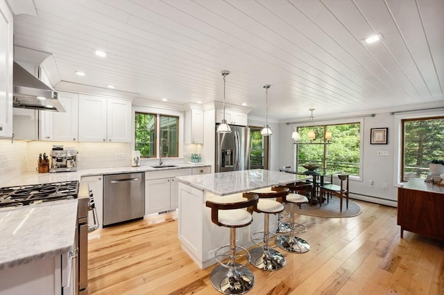 15 Youngs Rd, Gloucester, MA 01930 - kitchen featuring stainless steel appliances, wall chimney exhaust hood, white cabinetry, a kitchen bar, and recessed lighting