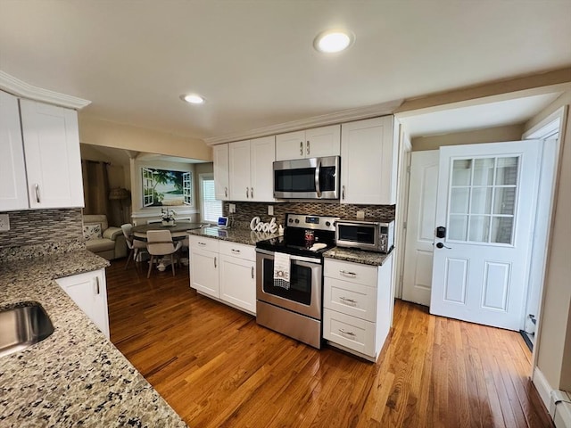 16 3rd St, Framingham, MA 01702 - kitchen with appliances with stainless steel finishes, wood finished floors, white cabinetry, and recessed lighting