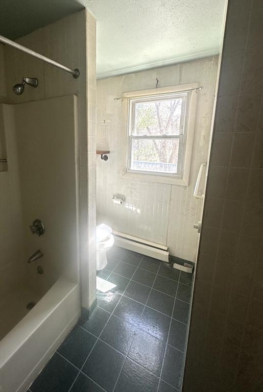 full bathroom featuring a baseboard heating unit, bathing tub / shower combination, toilet, a textured ceiling, and tile patterned flooring