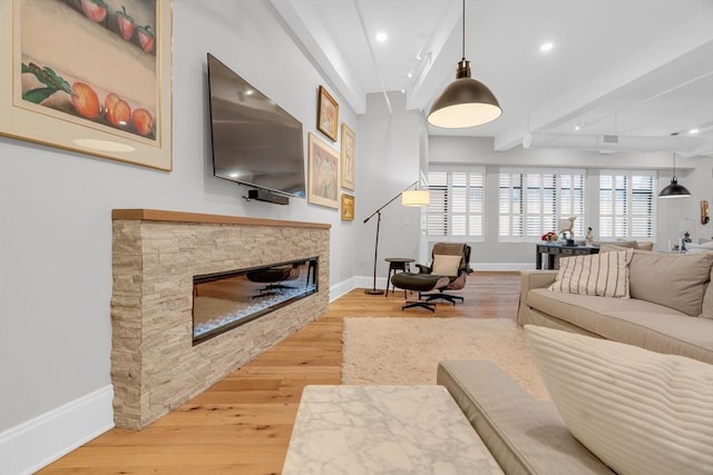 living area with a stone fireplace, recessed lighting, wood finished floors, and baseboards