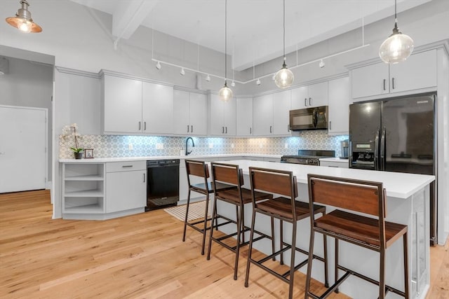 kitchen with light countertops, light wood-style flooring, backsplash, beamed ceiling, and black appliances