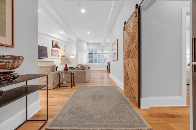 hall featuring baseboards, a barn door, recessed lighting, and light wood-style floors