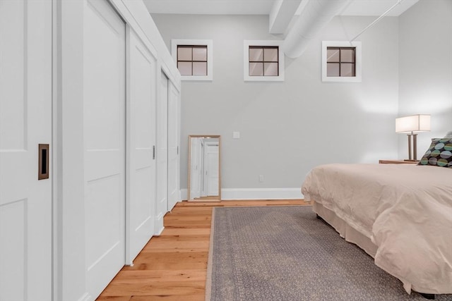 bedroom featuring light wood-type flooring, a closet, and baseboards