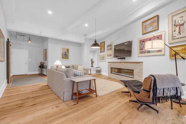 living room with recessed lighting, a stone fireplace, baseboards, and wood finished floors