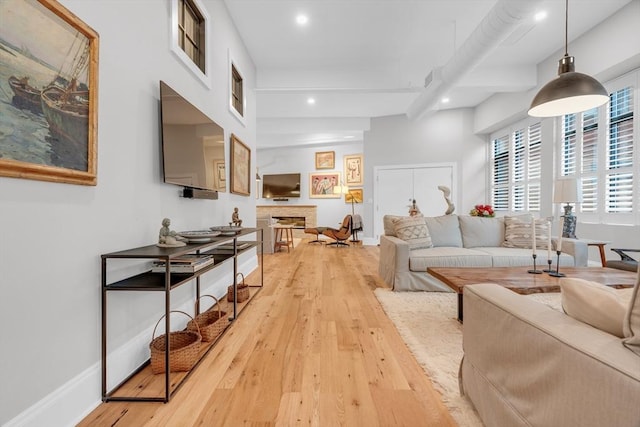 living area featuring light wood-type flooring, a fireplace, baseboards, and recessed lighting