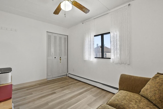 sitting room featuring ceiling fan, a baseboard heating unit, and wood finished floors