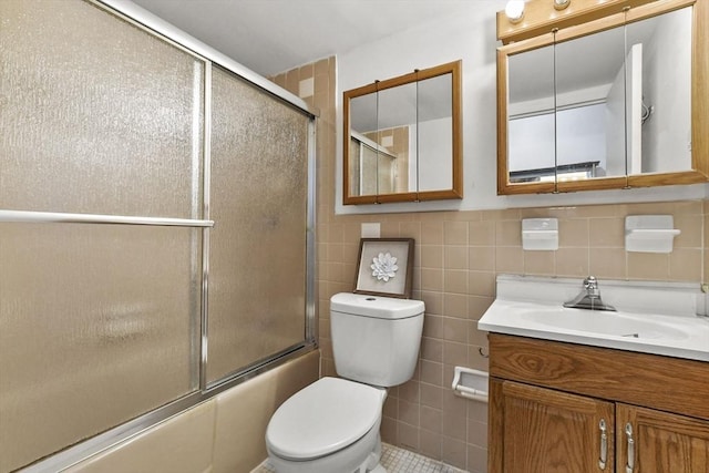 bathroom featuring shower / bath combination with glass door, tile walls, toilet, and vanity