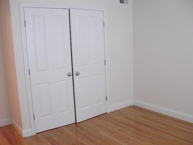 unfurnished bedroom with a closet, light wood-style flooring, and baseboards