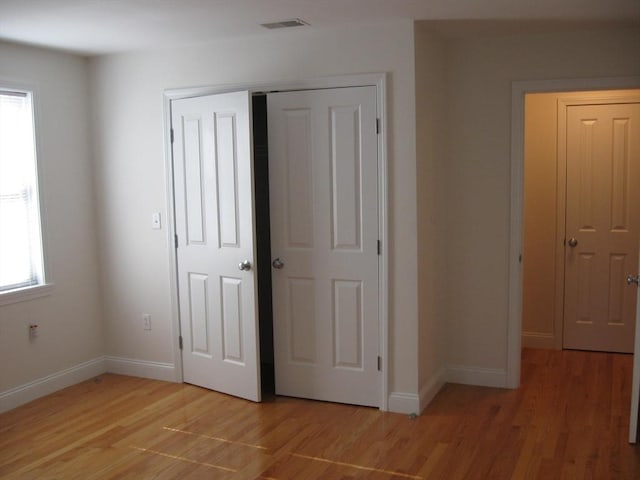 unfurnished bedroom with a closet, visible vents, light wood-style flooring, and baseboards