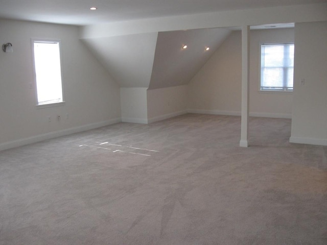 additional living space featuring lofted ceiling, a wealth of natural light, and light carpet