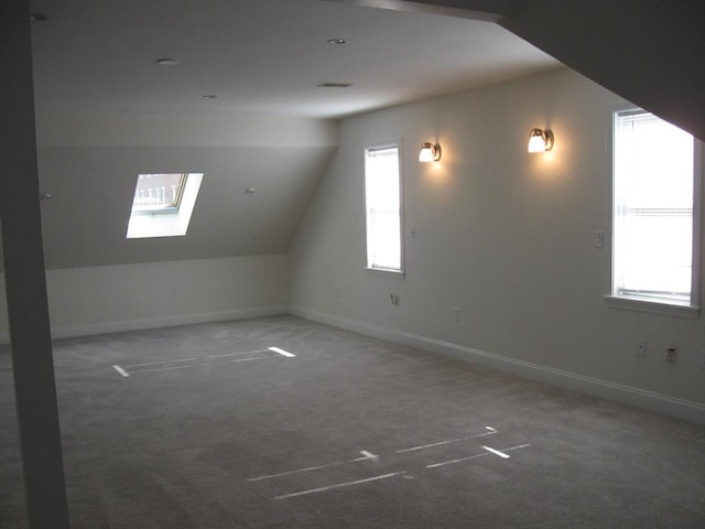 additional living space featuring baseboards, carpet floors, and lofted ceiling with skylight
