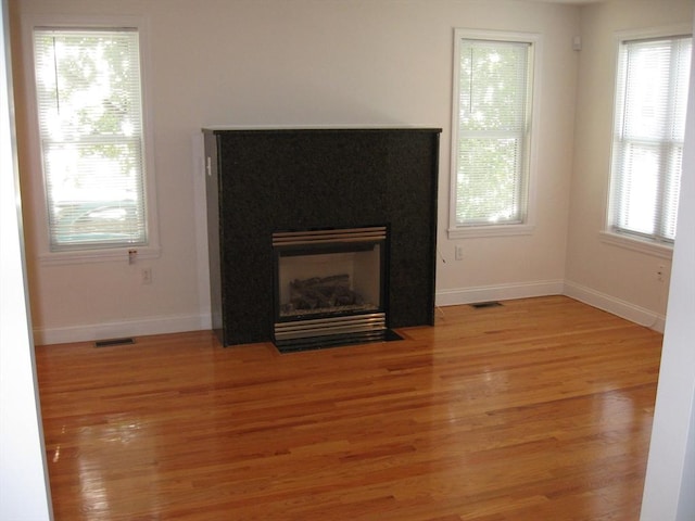 unfurnished living room featuring visible vents, a healthy amount of sunlight, and light wood-type flooring