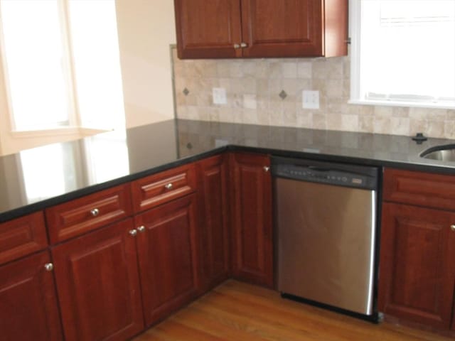 kitchen with dark countertops, dishwasher, backsplash, and light wood-style floors
